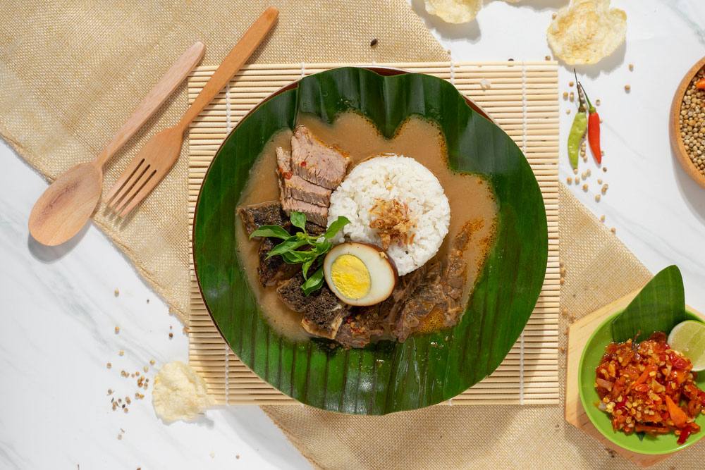 Seporsi Nasi Gandul khas Pati dengan kuah gurih berwarna cokelat pekat dan potongan daging sapi yang empuk