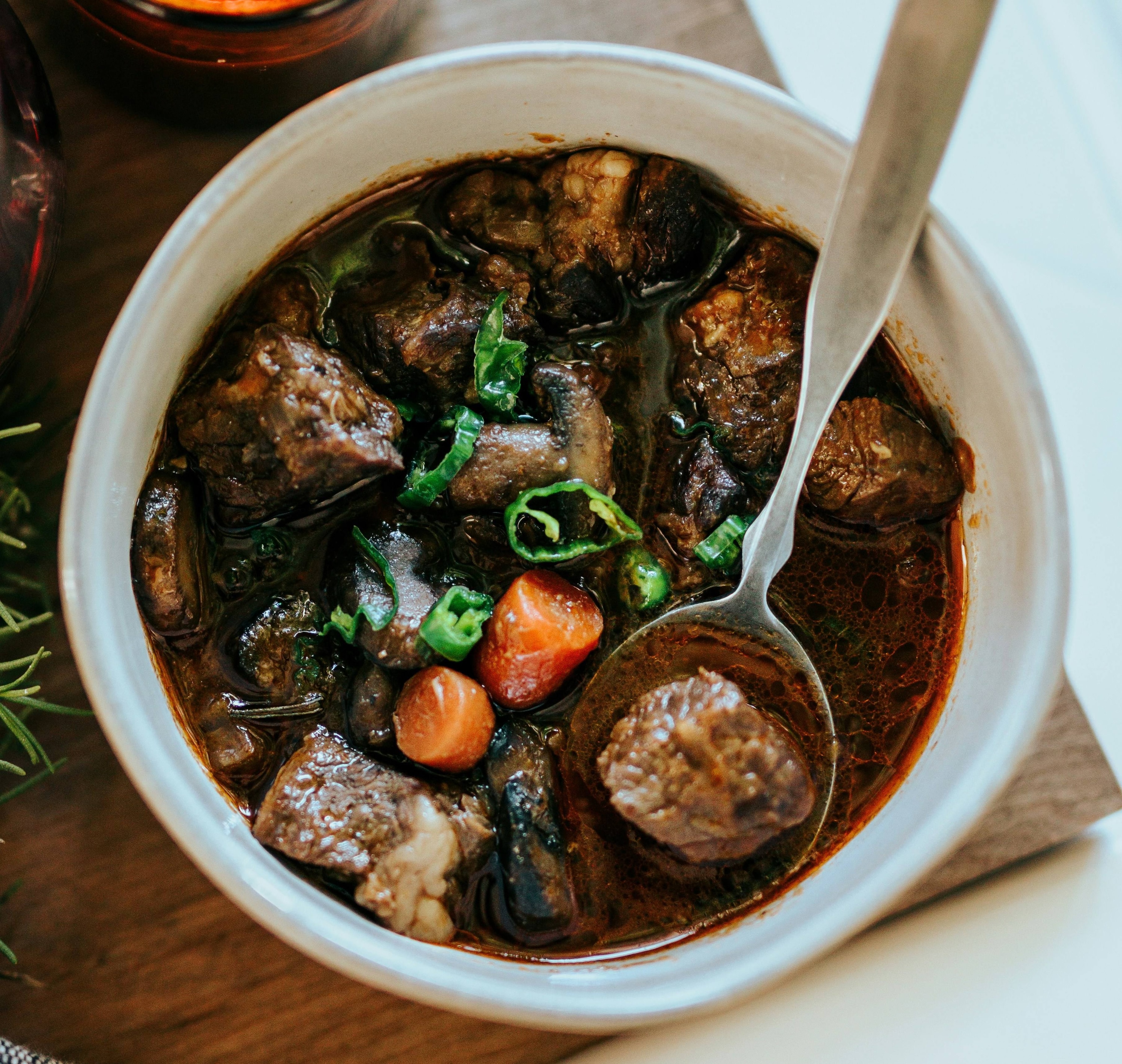 Tiyula Itum, black beef soup, inside a white bowl.