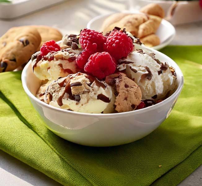 Scoops of non-dairy ice cream topped with raspberries in a bowl