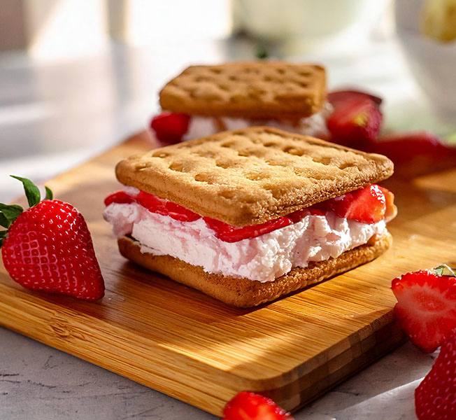 Strawberry daiquiri ice cream sandwiches on a wooden chopping board