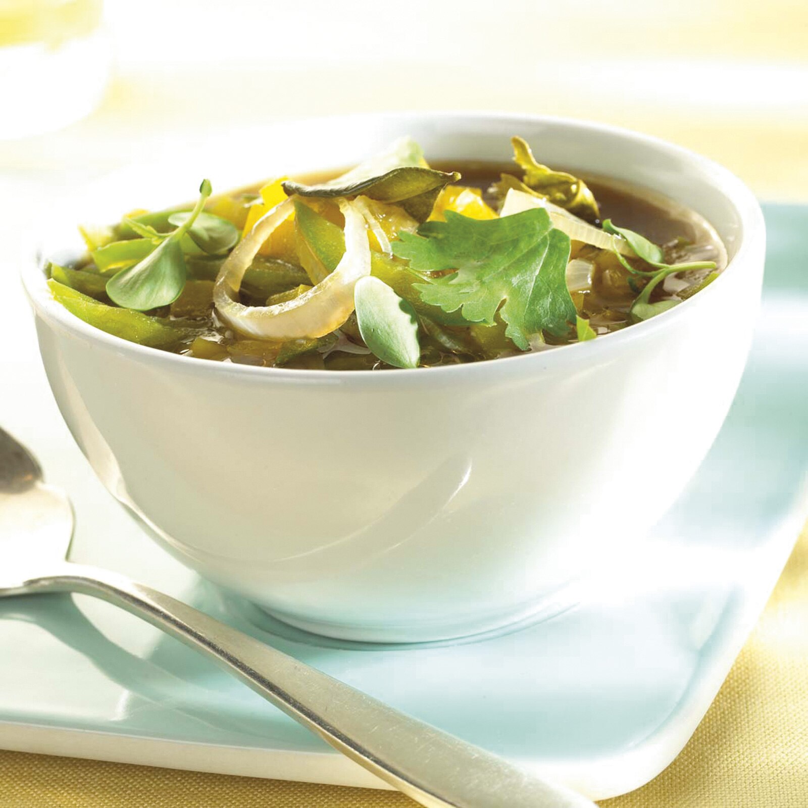 Consommé avec des oignons de printemps, des cosses de pois, du citron et de la coriandre