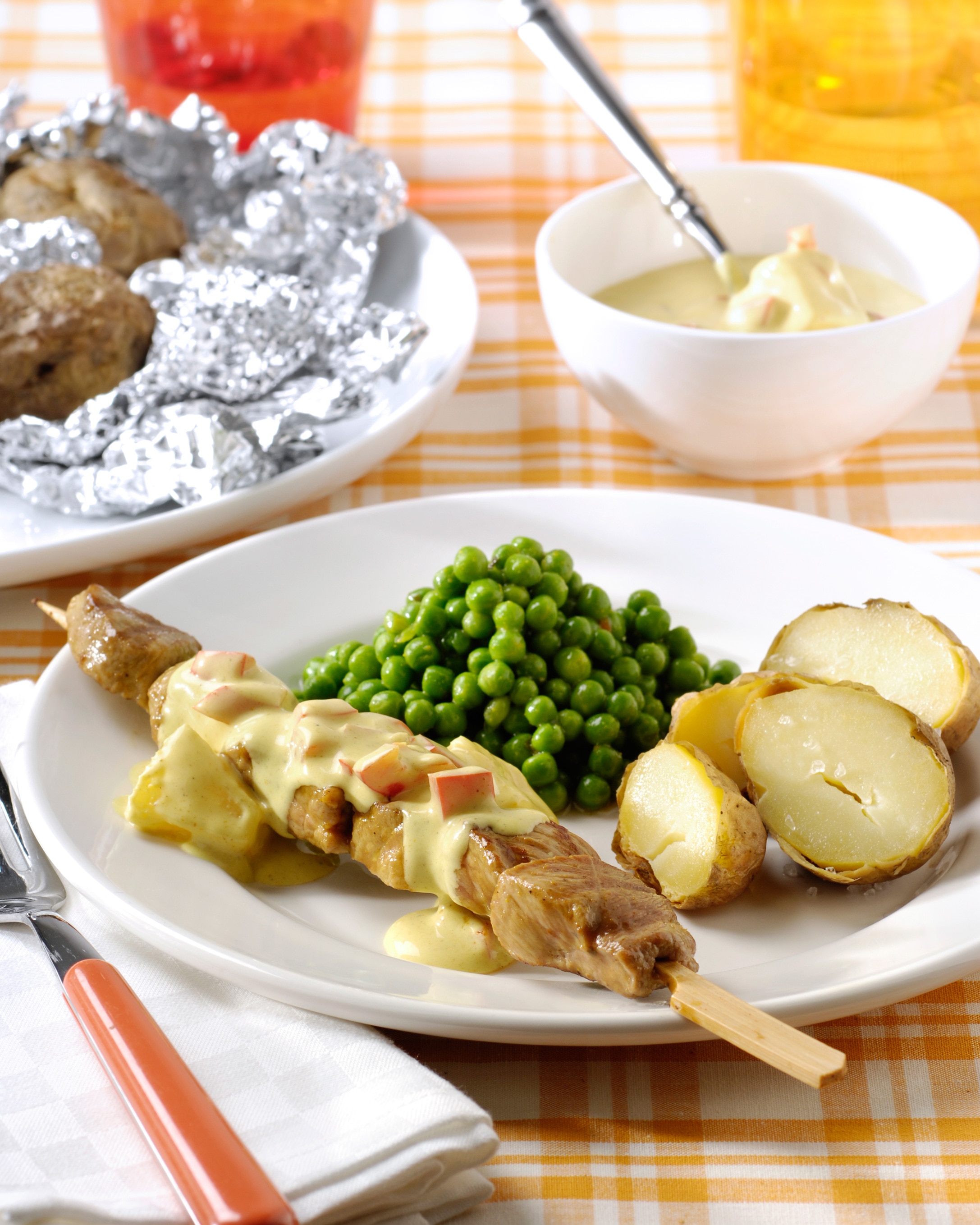 Brochettes de viande, sauce au curry, petits pois et pommes de terre soufflées