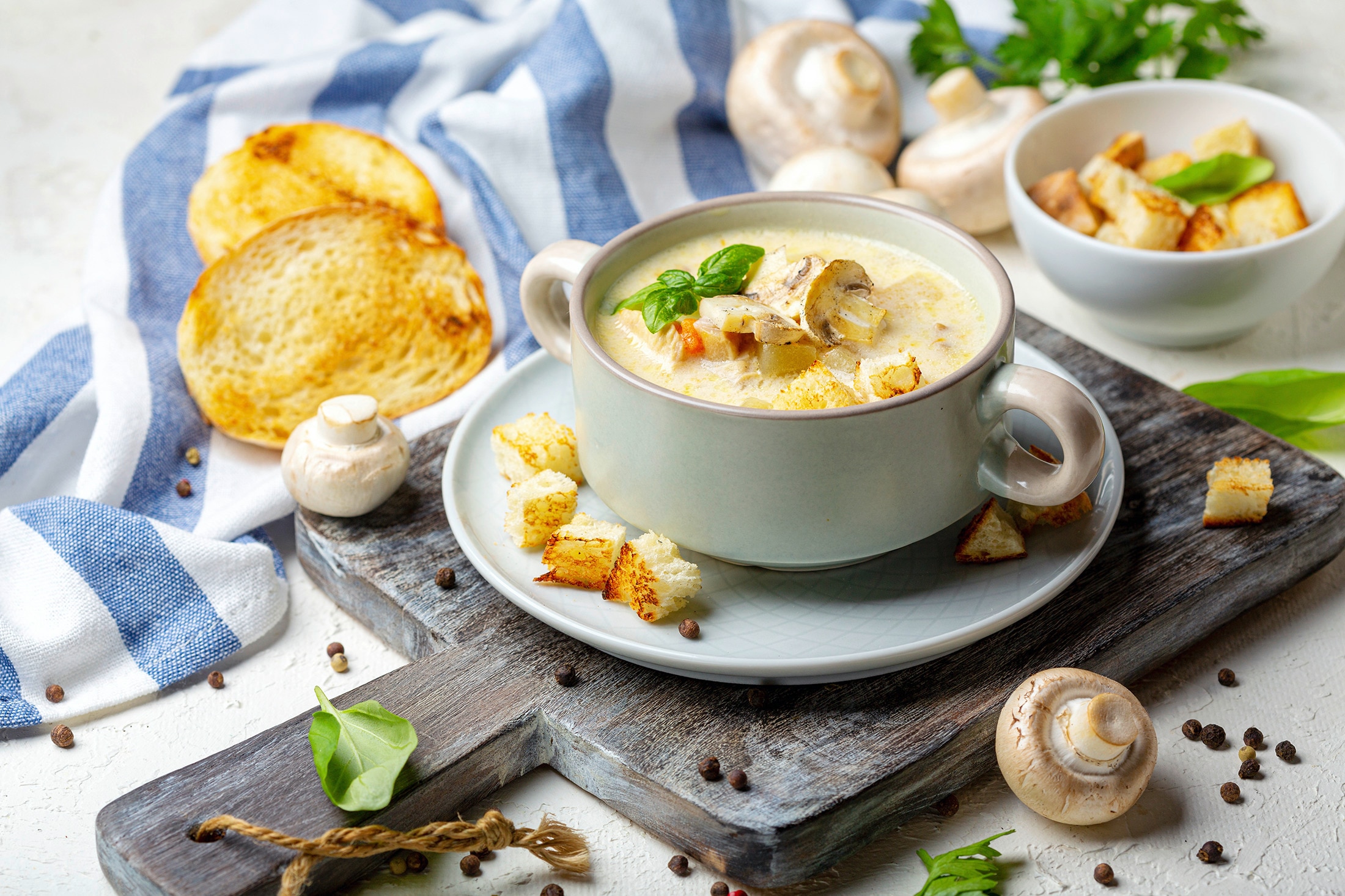 A cup of mushroom soup with croutons and sliced mushrooms