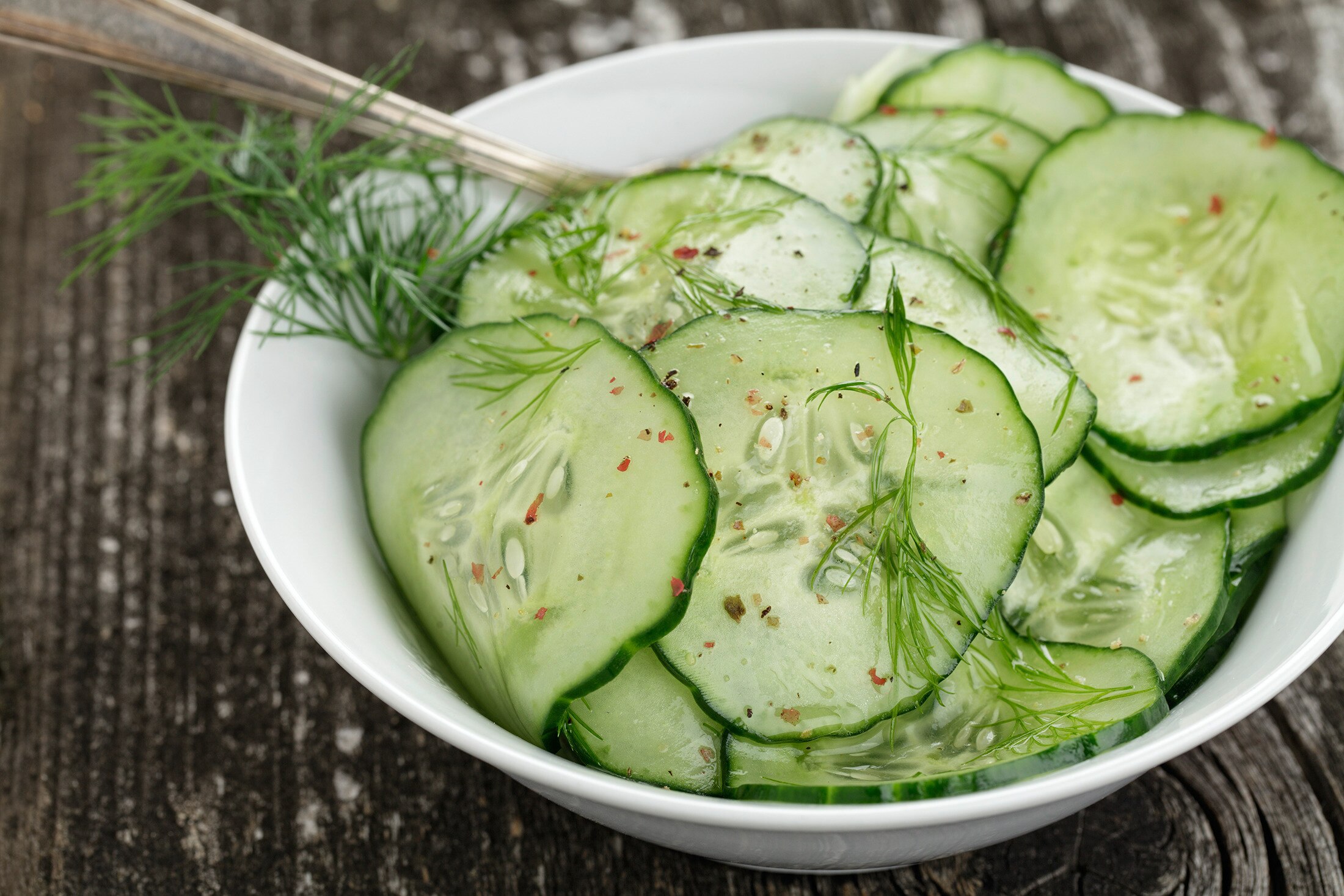A bowl of thinly sliced cucumber with a simple vinegar dressing