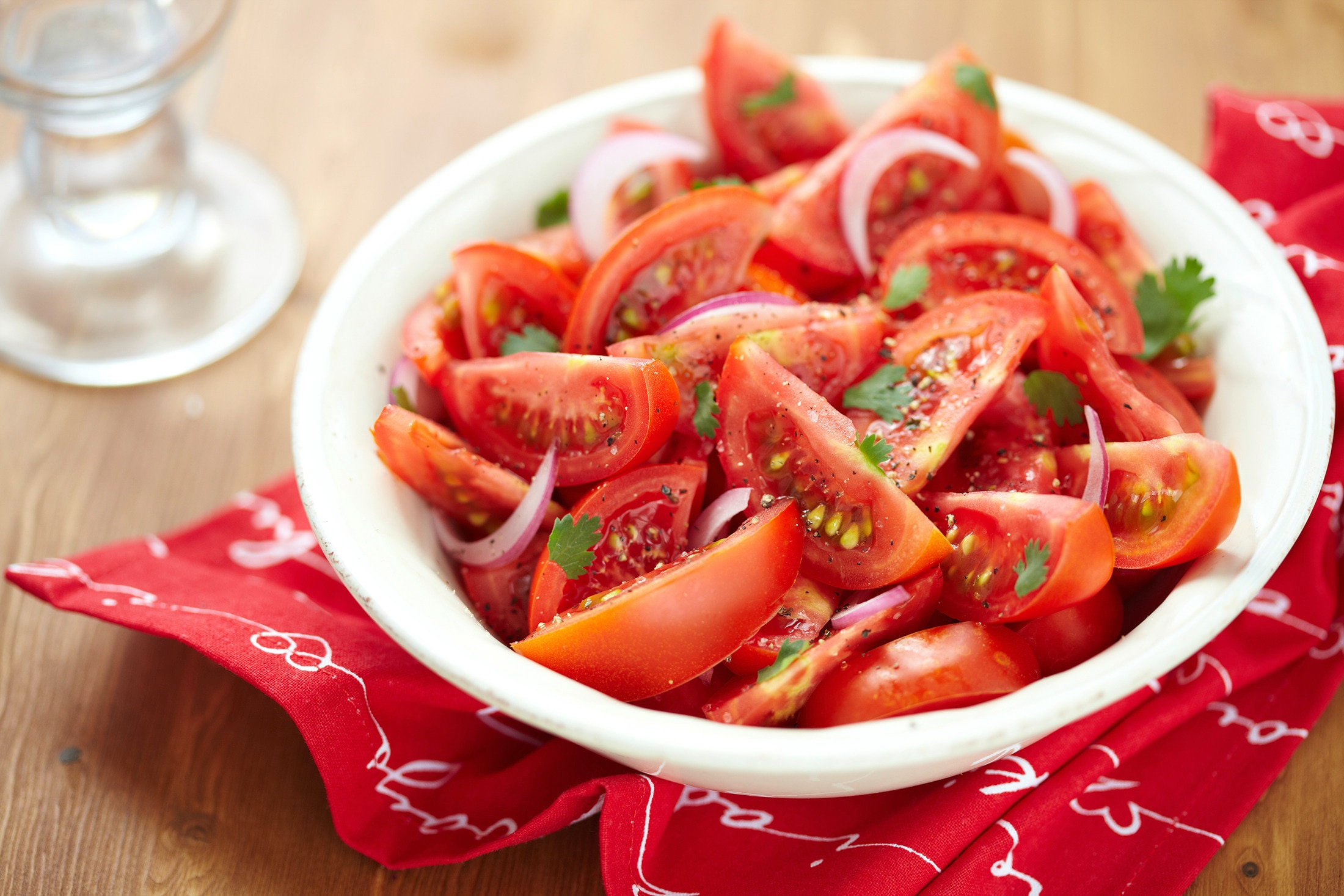 A bowl of tomato wedges with sliced red onions