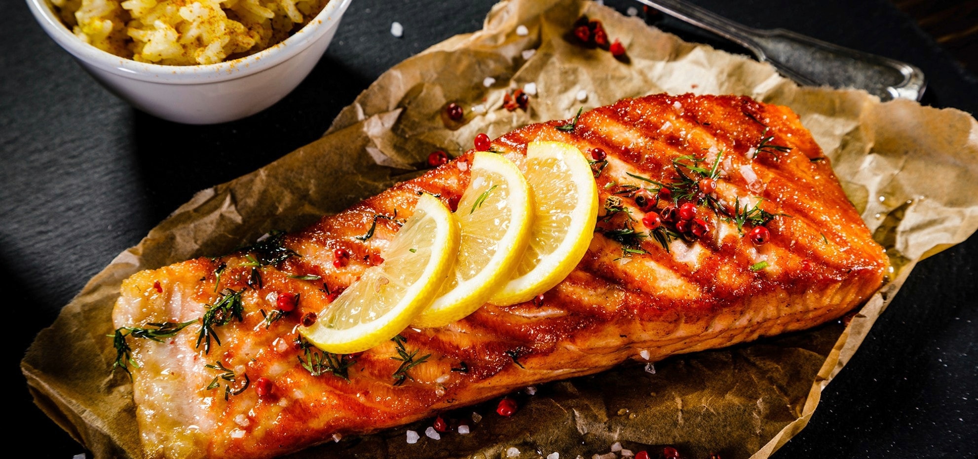 Grilled salmon with lemon slices on a baking dish lined with parchment paper