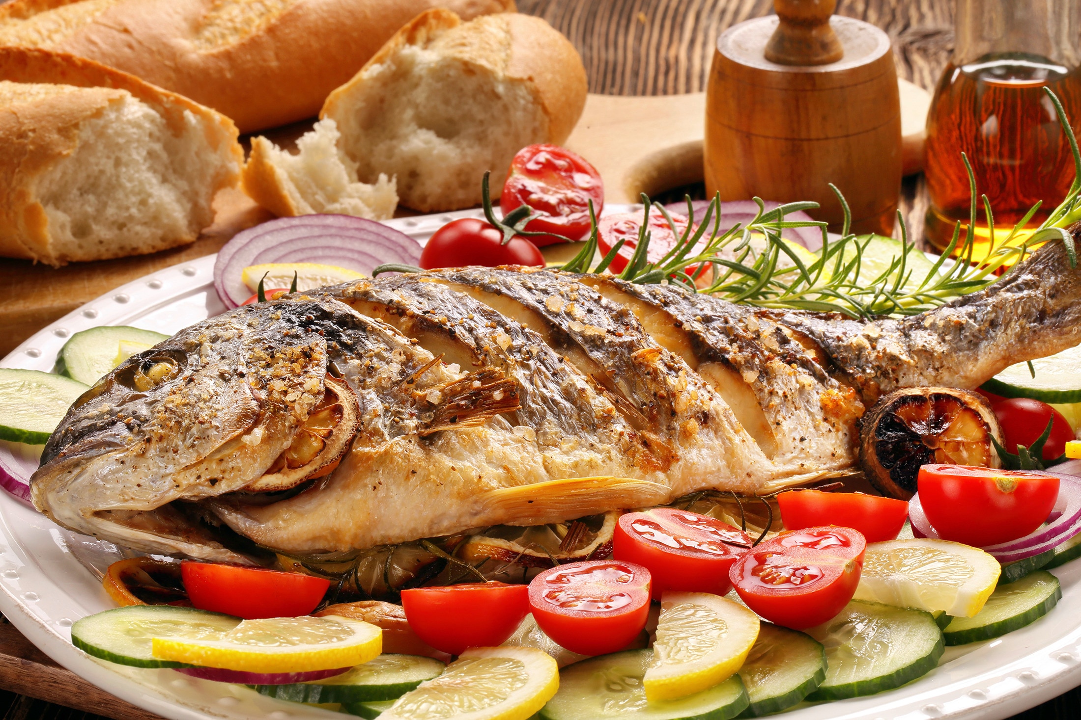 A platter of grilled fish on a bed of fresh vegetables