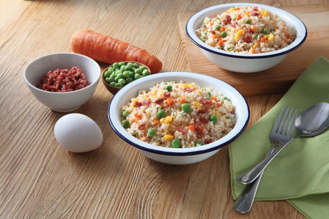 Corned beef fried rice served in a bowl, surrounded with ingredients