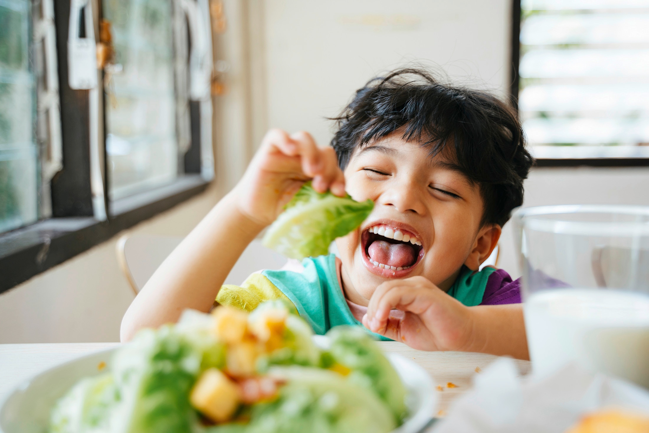 A young boy happily eating leafy vegetables