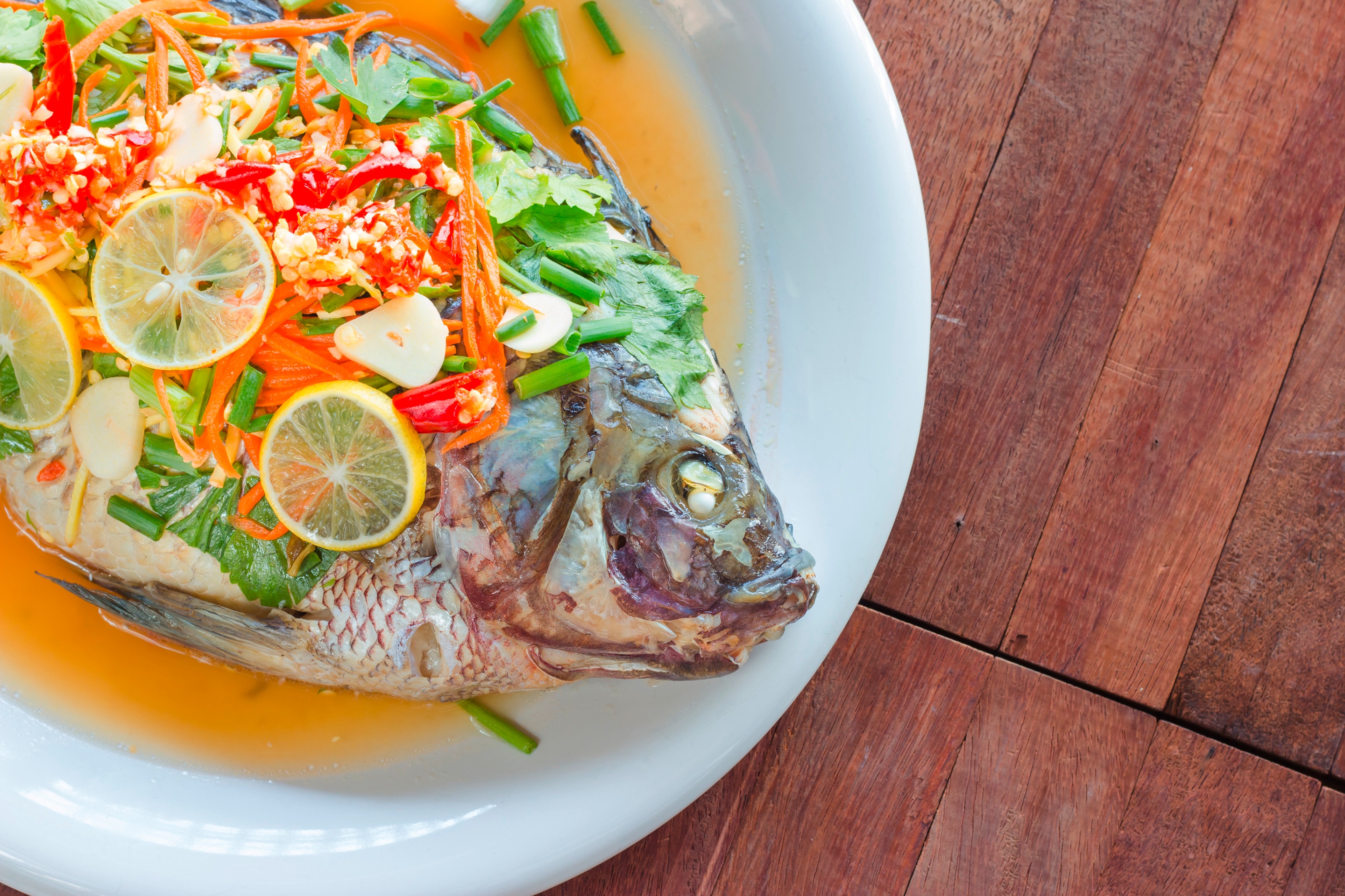 Steamed tilapia with lemon slices, chilies, and green onions