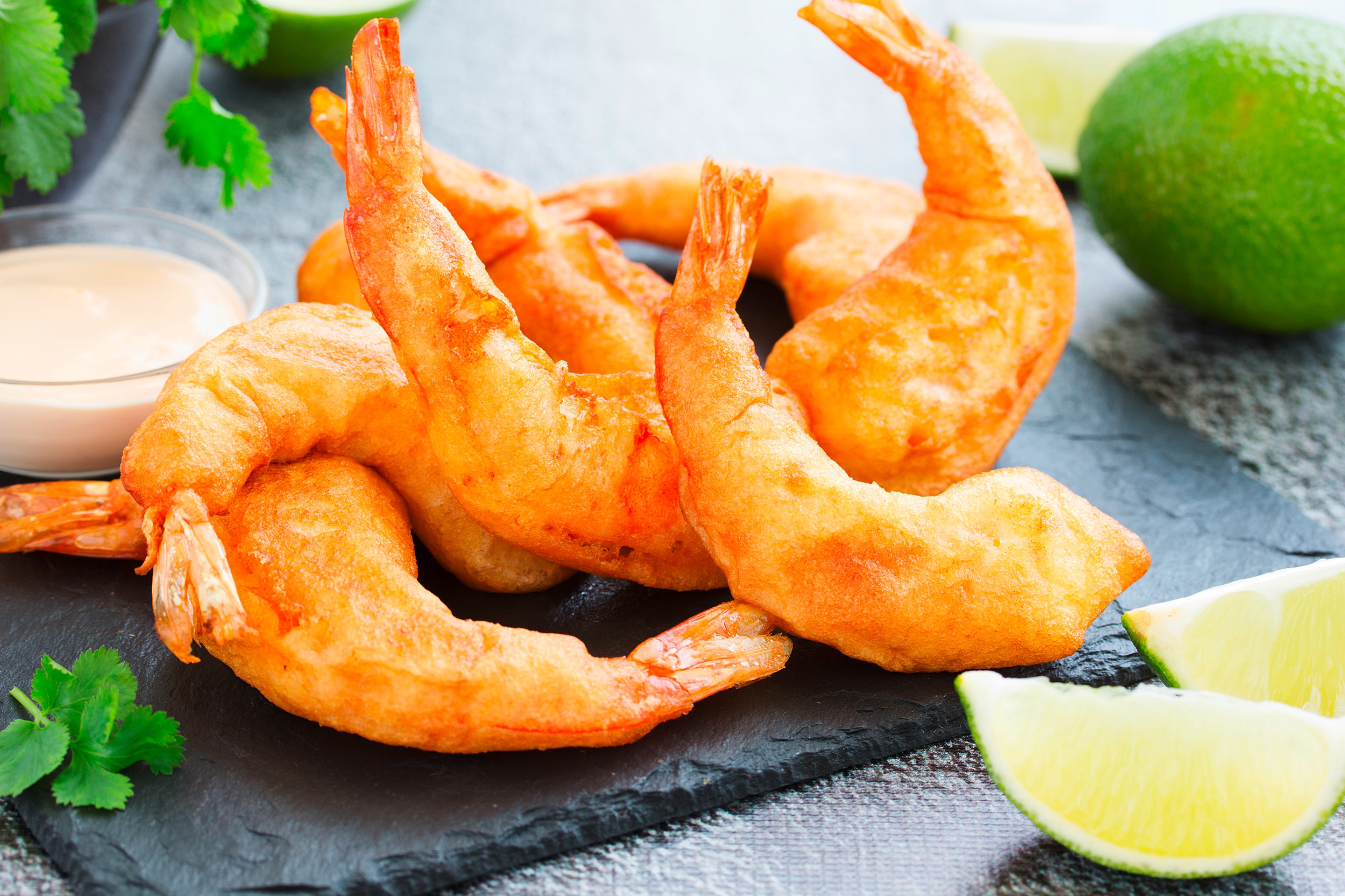 A serving of fried shrimp with fresh limes and a mayo dipping sauce