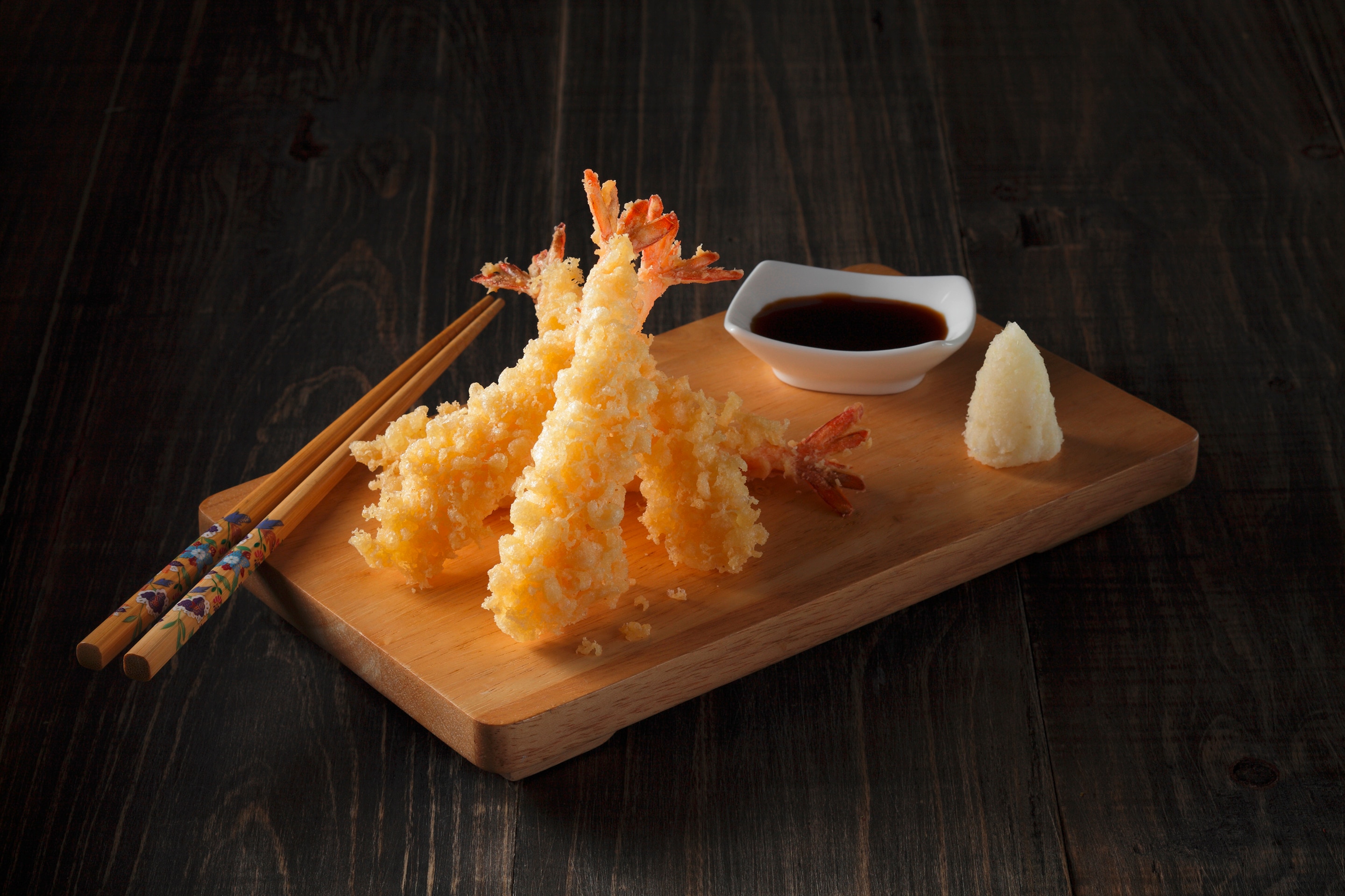 A serving of Japanese shrimp tempura with soy sauce on a wooden tray