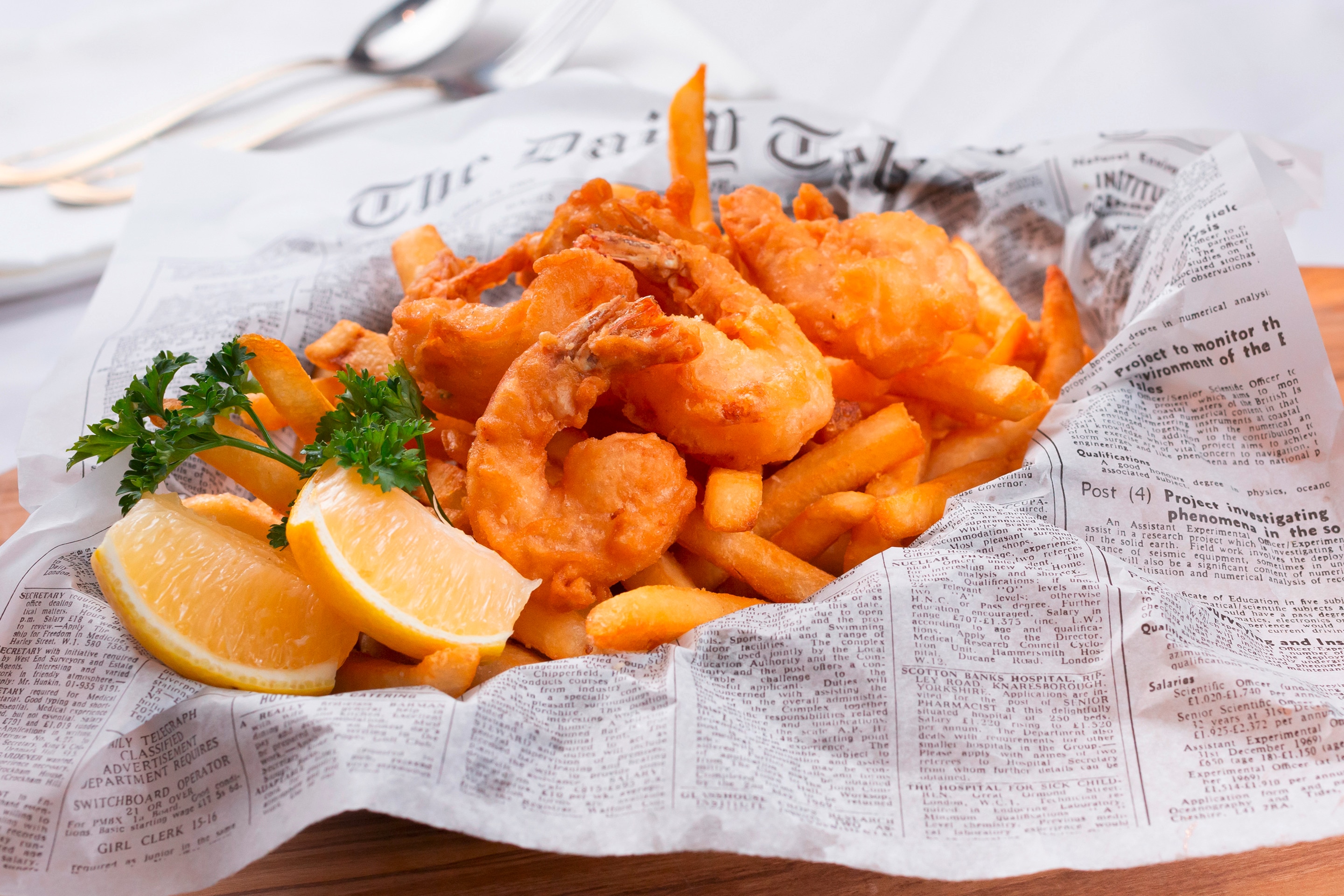 A basket of battered shrimp with French fries and fresh lemons