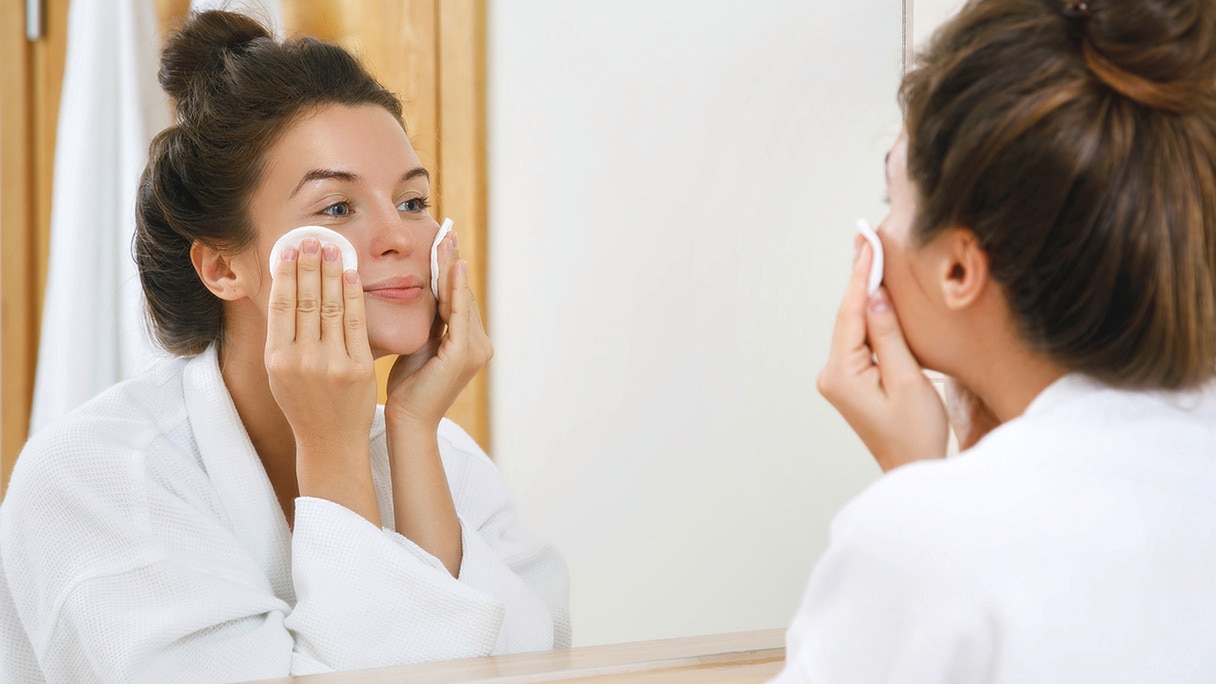 Woman washing her face using two cotton pads