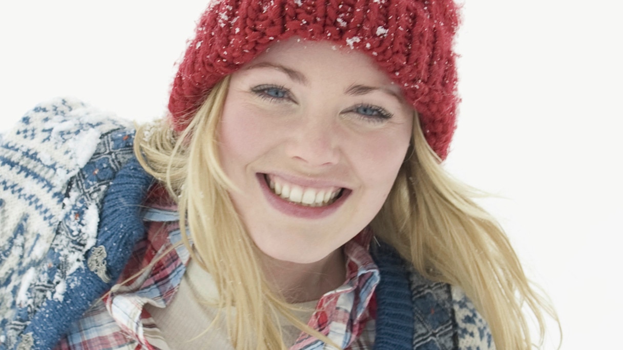 Smiling woman wearing a red beanie in the snow