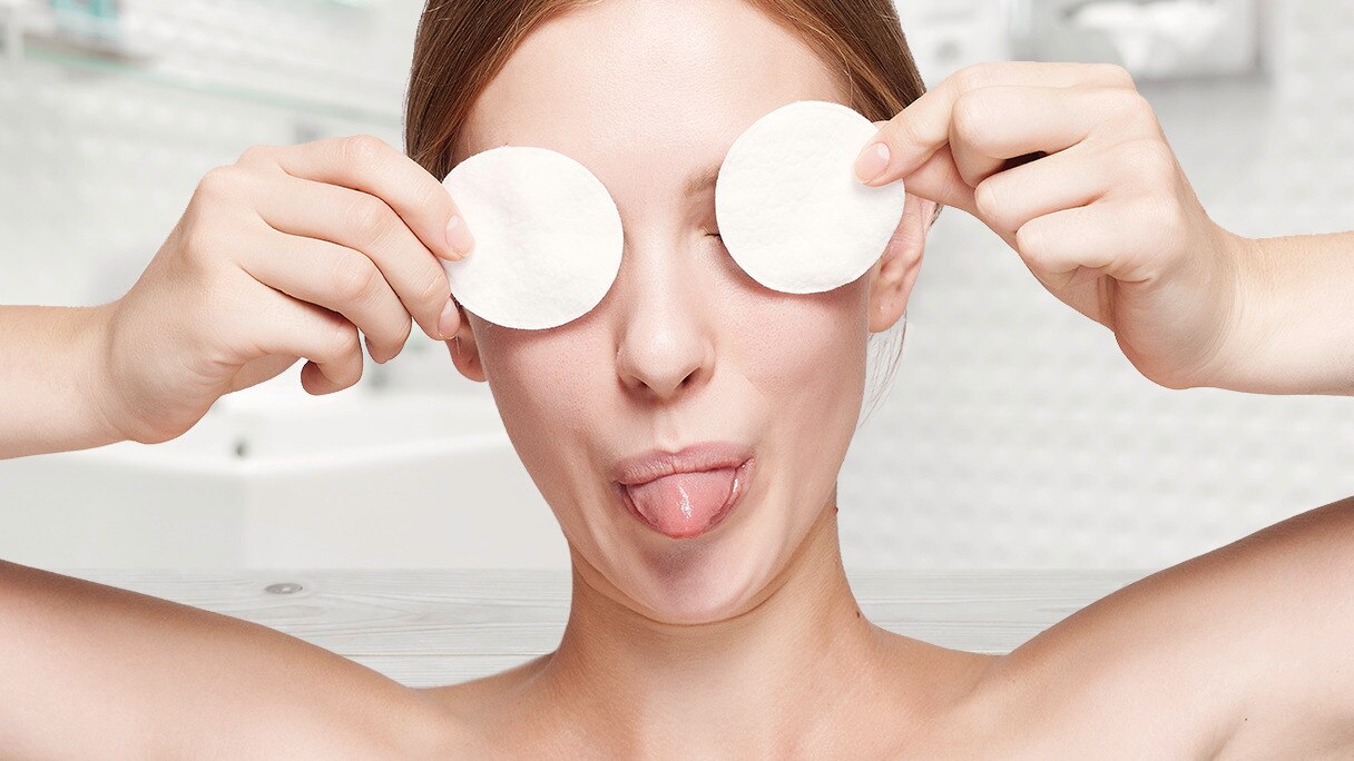 หญิงสาววางแผ่นสำลีบนเปลือกตาในห้องน้ำ