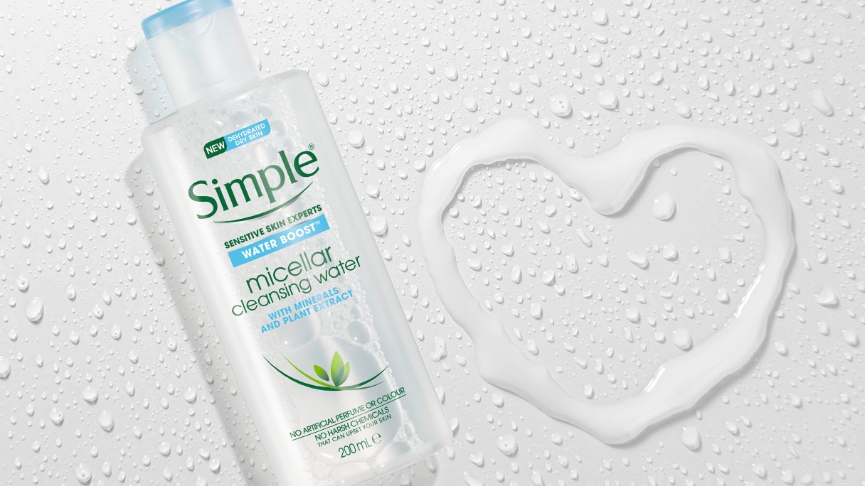 A bottle of Simple Micellar Cleansing Water on a grey background with water droplets in the shape of a heart
