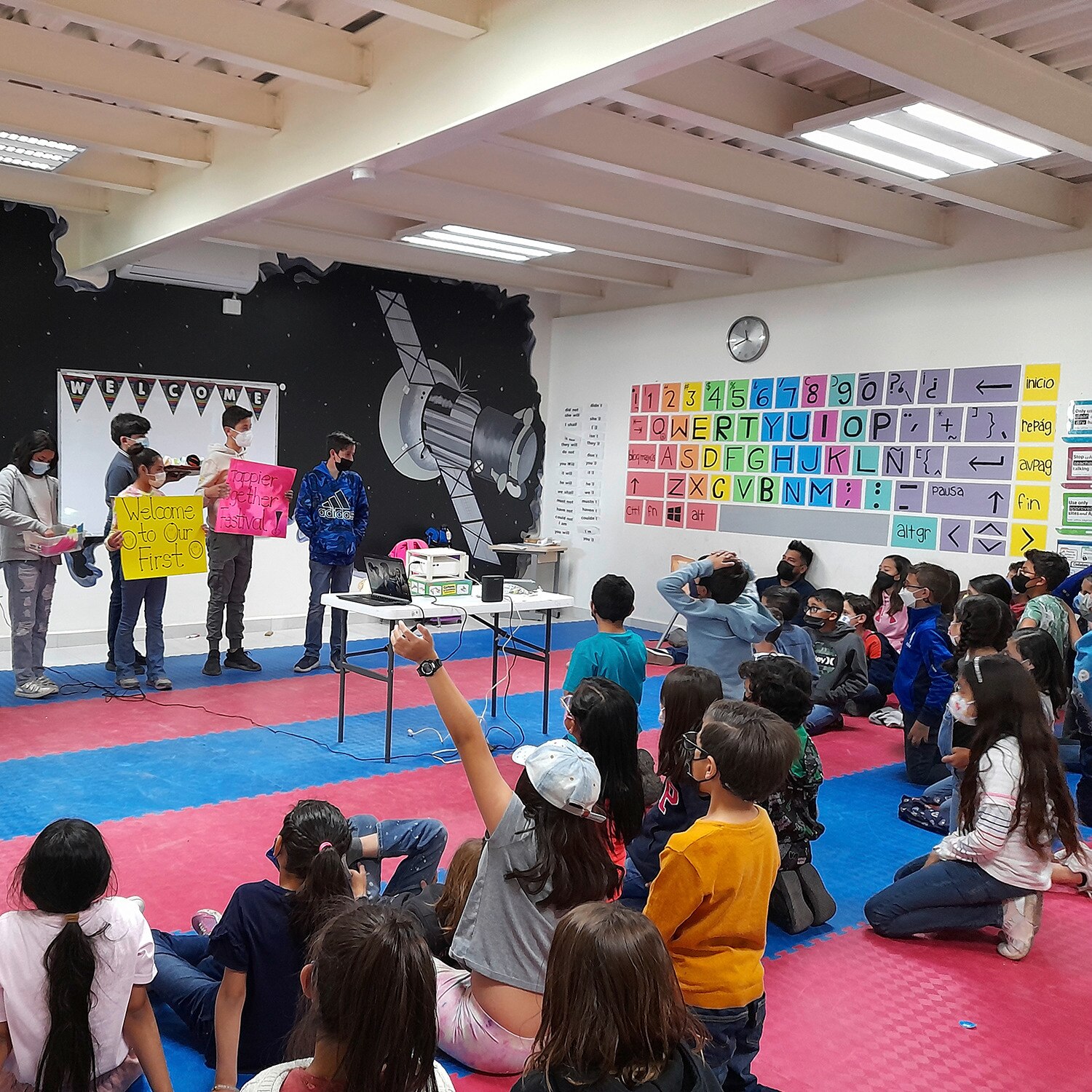 En grupp unga studenter som presenterar sin lyckofestival för resten av sina klasskamrater i ett färgstarkt klassrum