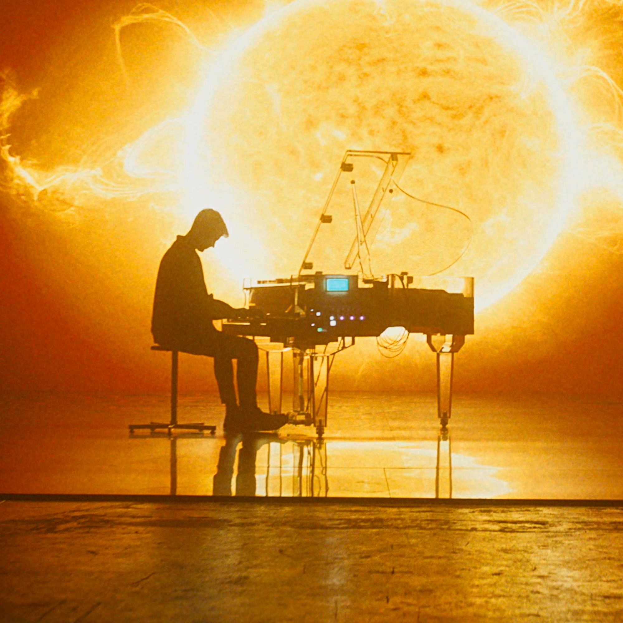 Homme jouant du piano devant une vidéo géante d'explosion de soleil