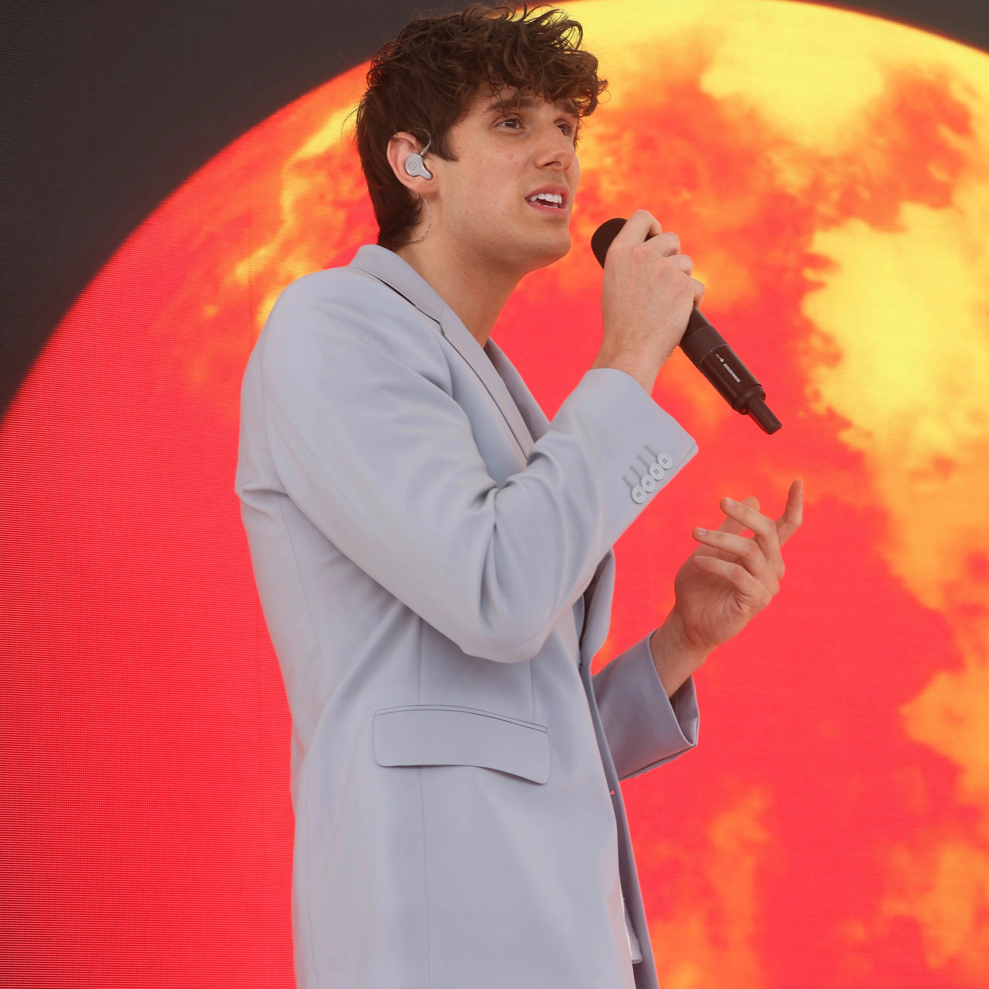 JVKE singing in front of a large sun image