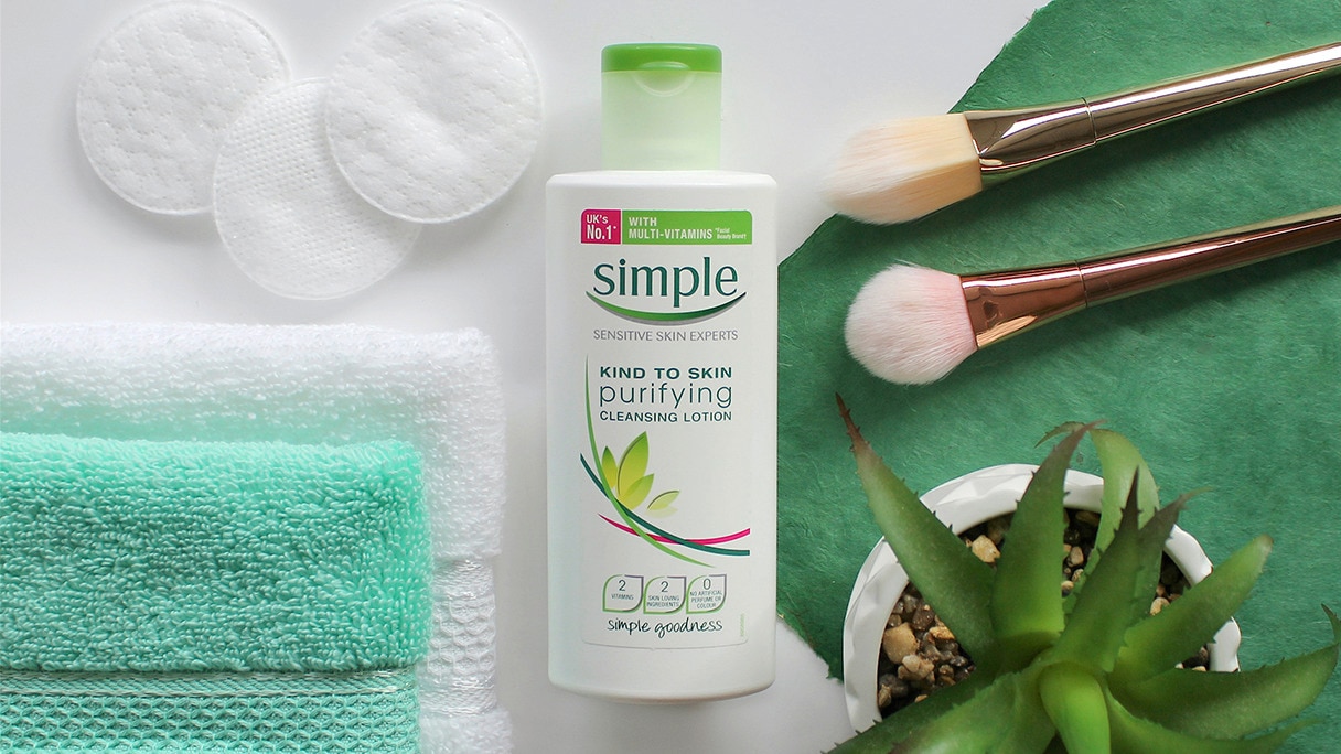 Simple Purifying Cleansing Lotion on a white background alongside make-up brushes, face cloths and cotton pads. 