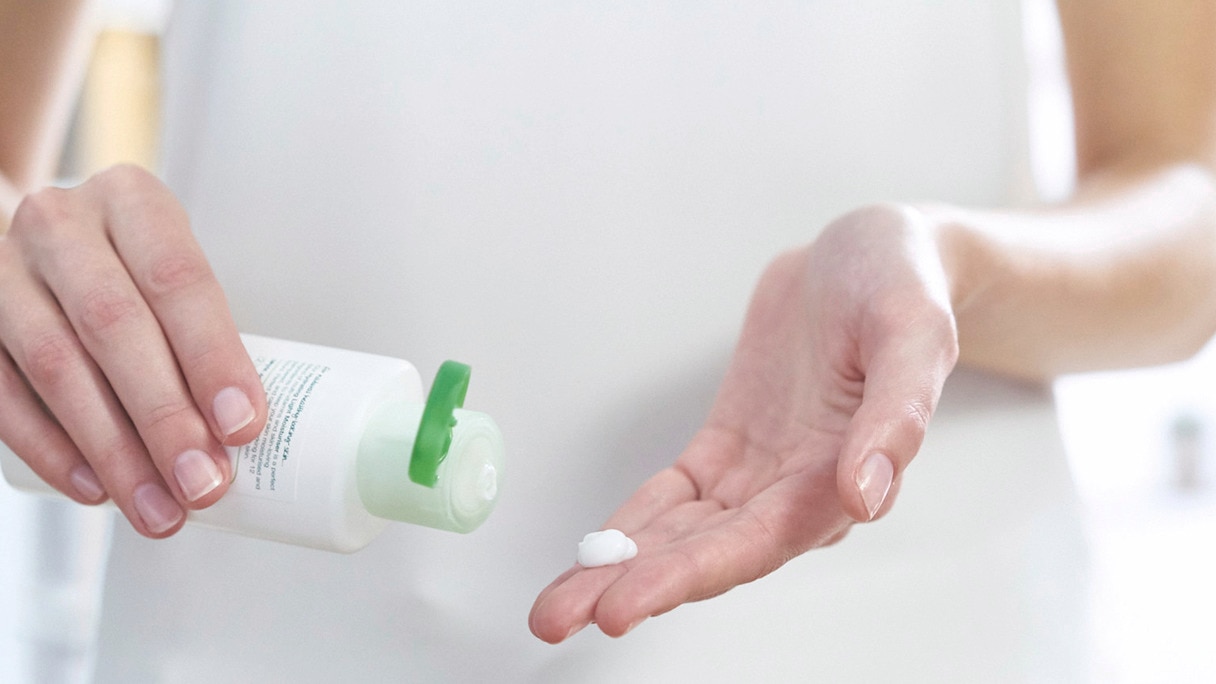 Woman squeezing Simple moisturiser onto her fingertips Woman squeezing Simple moisturiser onto her fingertips