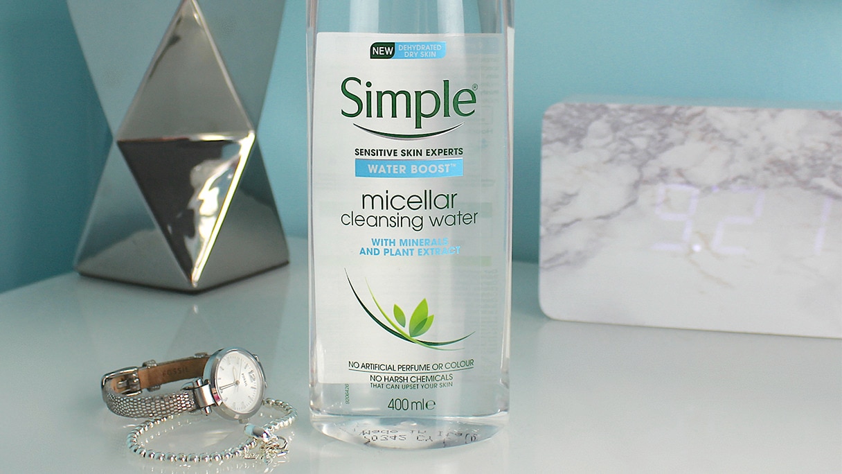 Simple Water Boost Micellar Cleansing Water on bedside table with lamp in the background Simple Water Boost Micellar Cleansing Water on bedside table with lamp in the background