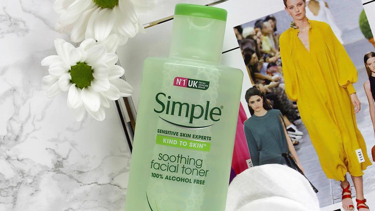 Bottle of Simple toner on a magazine page alongside cotton pads