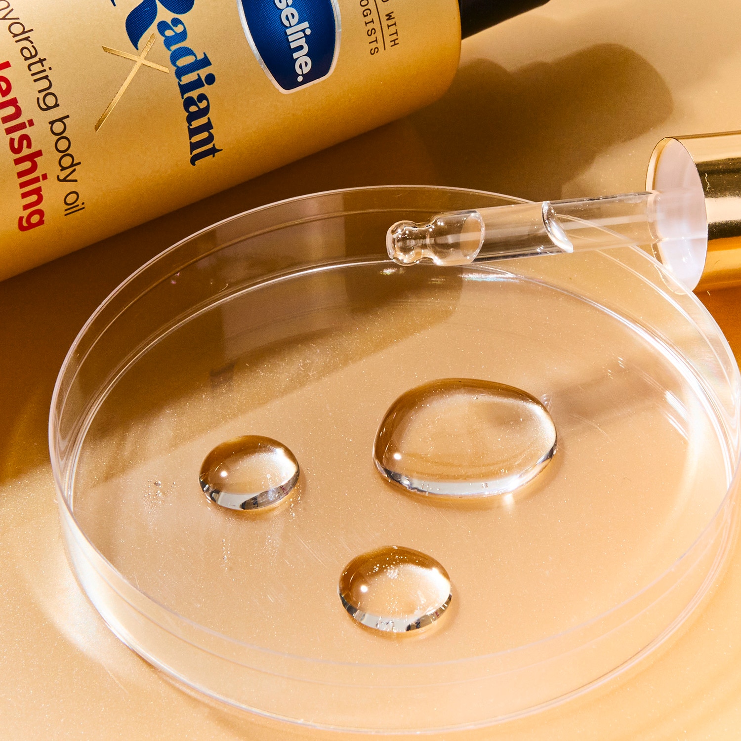 Droplets of Vaseline Radiant X Replenishing Body Oil placed in a petri dish