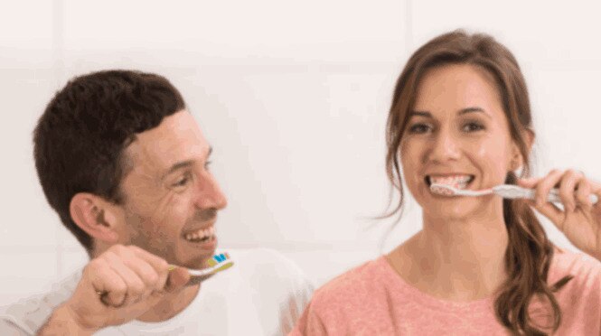 Một cặp đôi đang đánh răng và mỉm cười