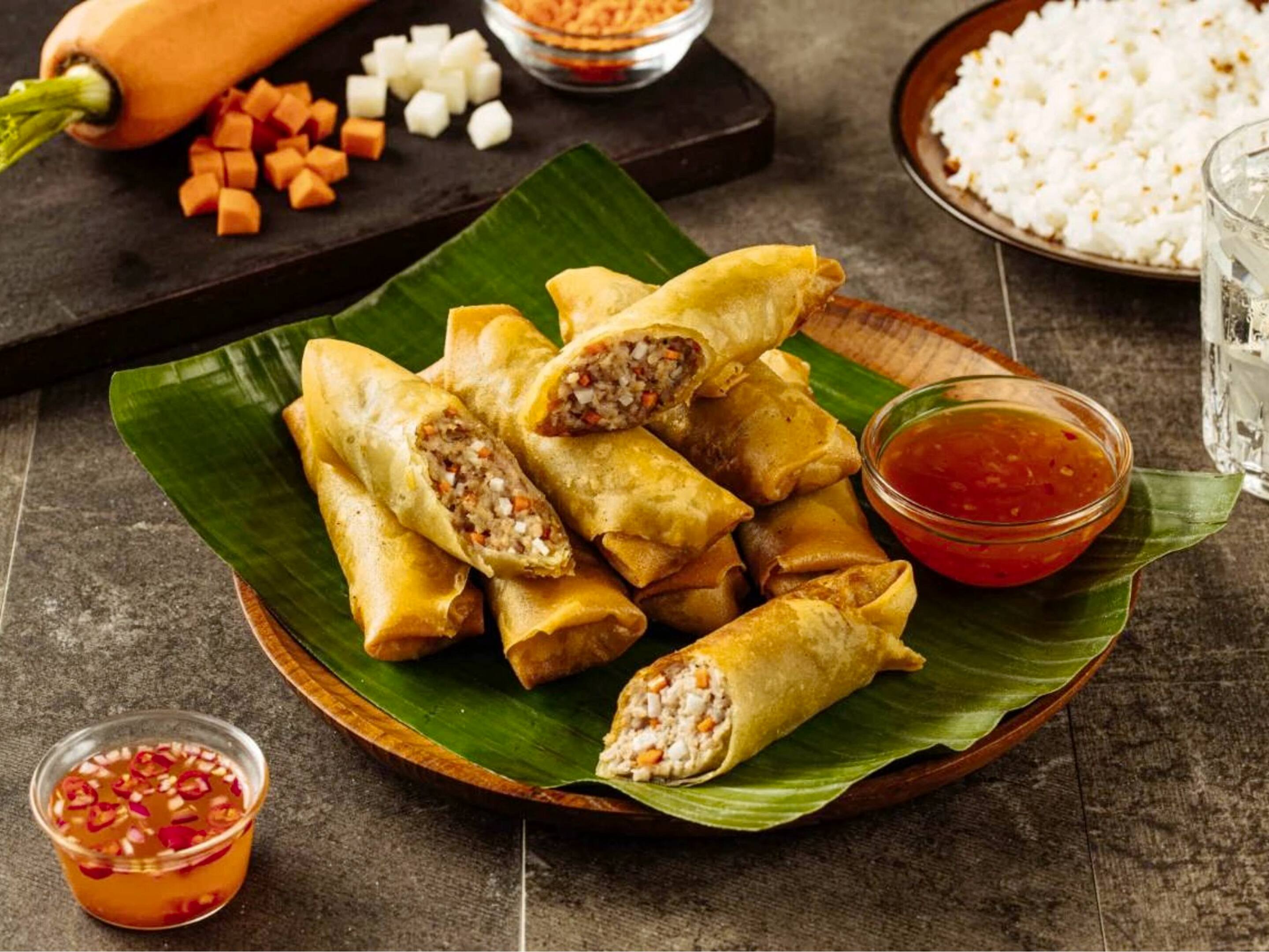 Lumpiang shanghai served with sweet chili sauce on a banana leaf