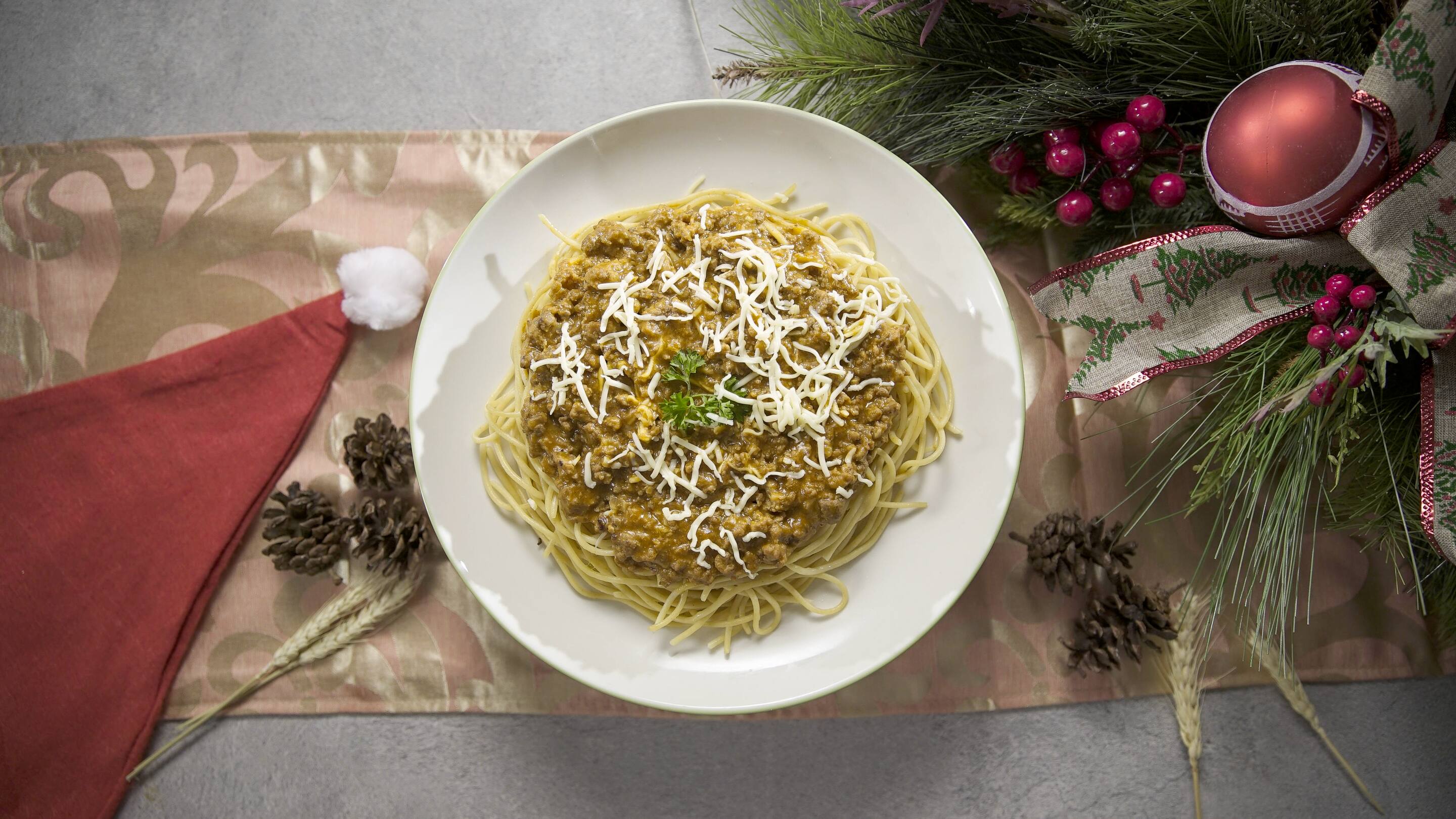 A large serving of creamy spaghetti on a table decorated with Christmas elements