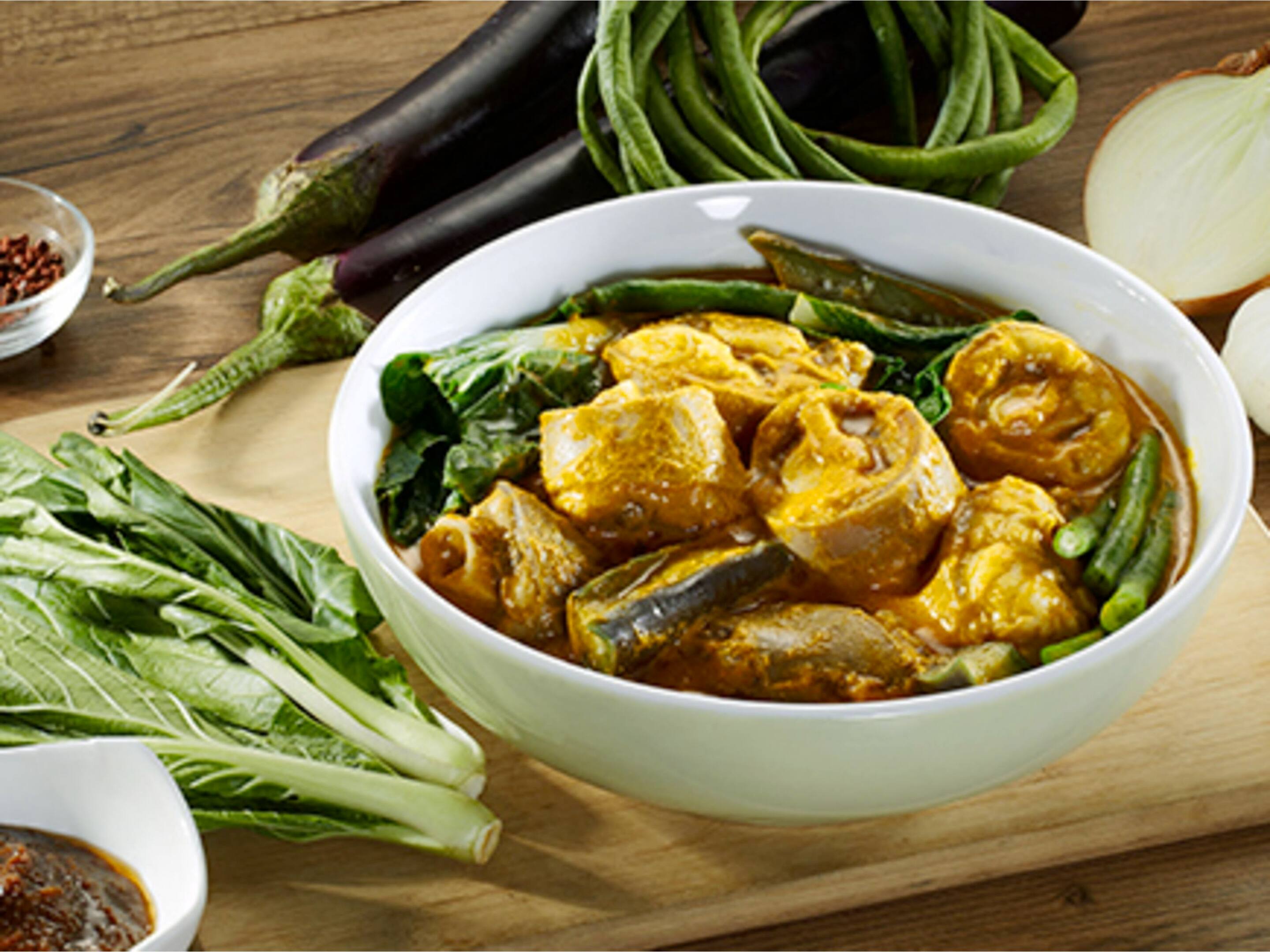 A bowl of Kare-Kare in creamy peanut sauce with eggplants, pechay, and string beans