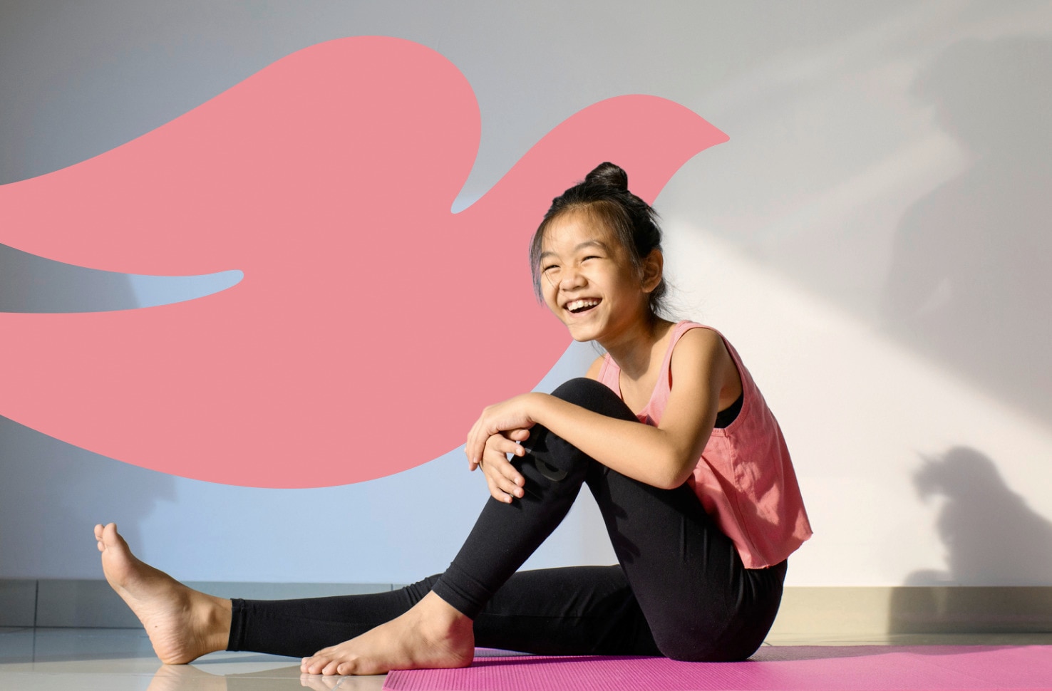 Young smiling girl sitting on a yoga mat in front of a pink Dove logo