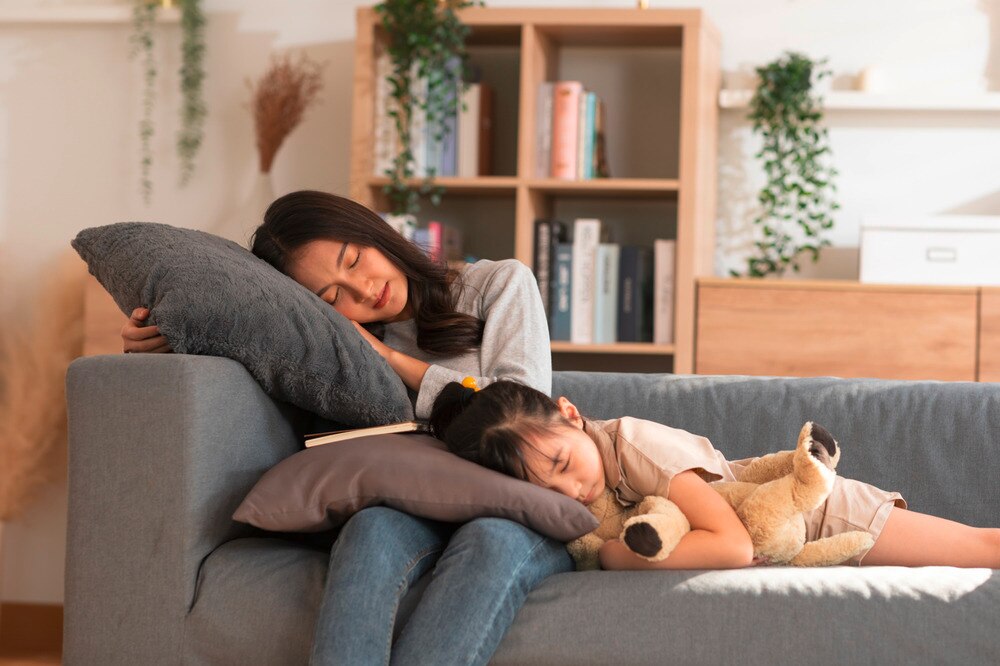 Asian mom and daughter sleeping on the couch.