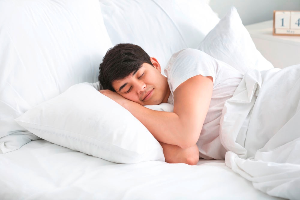 Asian man sleeping peacefully in bed.