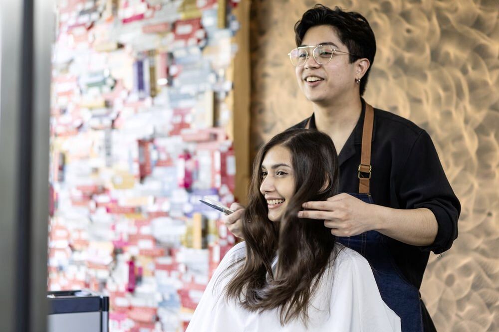 Asian woman getting her hair styled by a hairdresser.