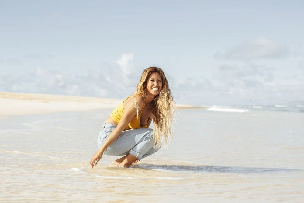 Asian girl with long curly blonde hair at wading in the water.