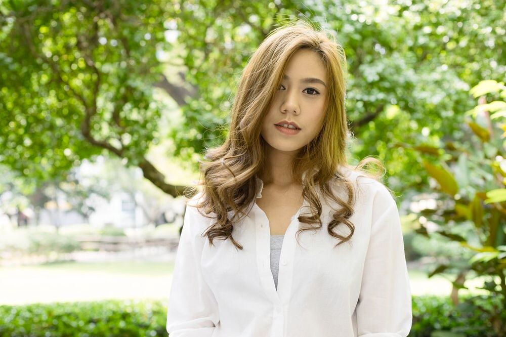 Portrait of a pretty Asian girl with wavy brown hair outdoors.