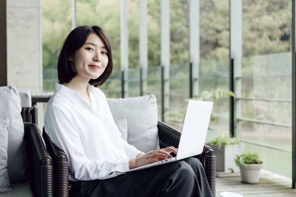 Profile of an Asian woman with soft layered hair, outdoors. 