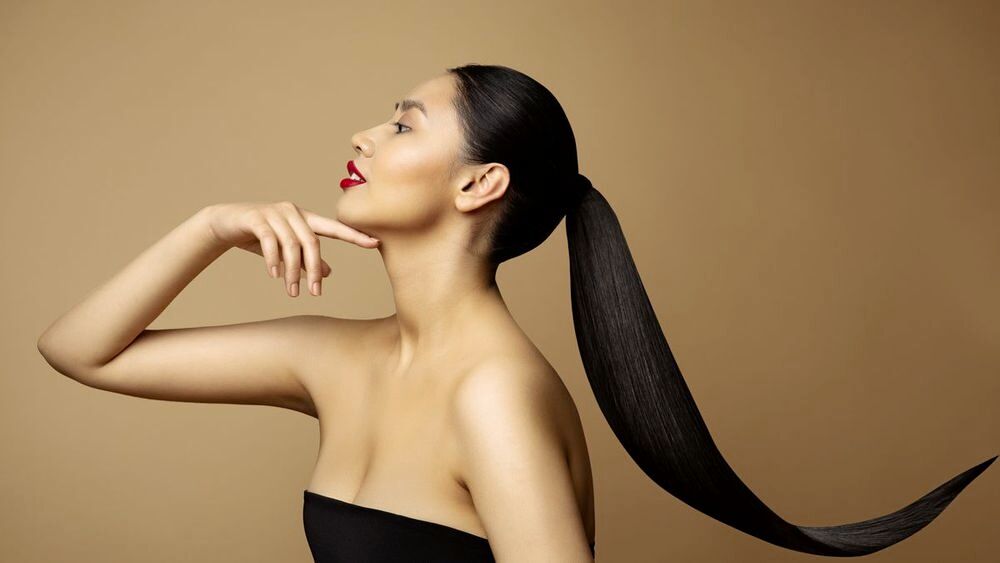 Profile of an Asian woman with long hair in a ponytail.
