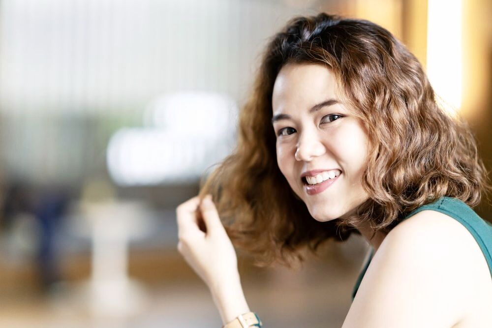 Smiling Asian woman playing with her wavy hair.