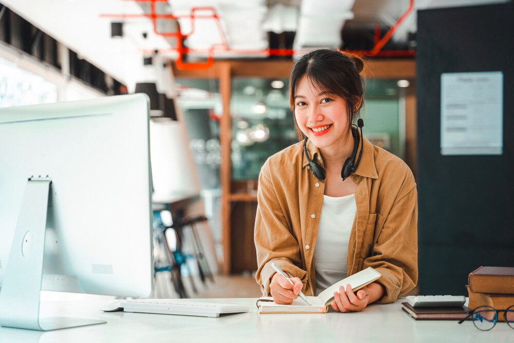 Asian woman with headphones around her neck at the office.