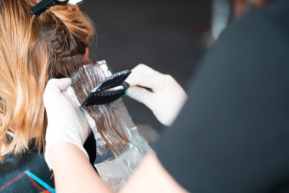 Back of a woman’s head while getting her hair colored at a salon.