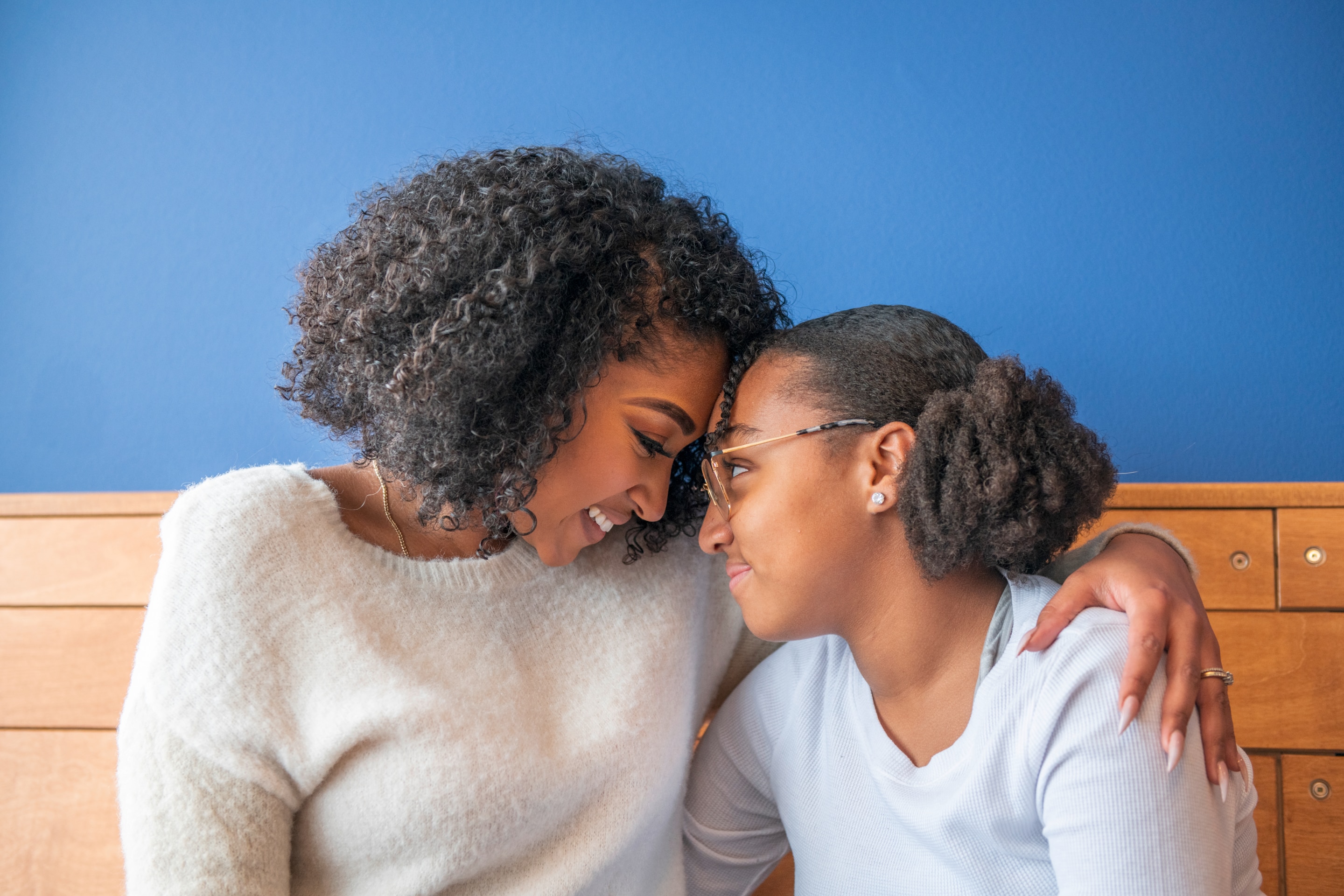 Black mother and daughter smiling and touching foreheads