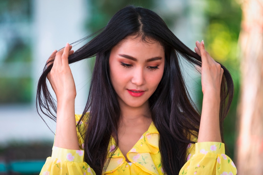 Woman combing her long black hair with her fingers.