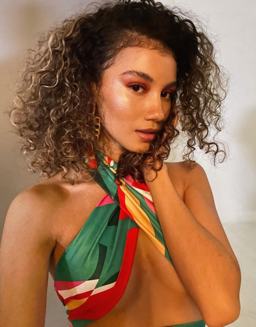 Nikki de Moura with curly hair wearing a printed halter top.