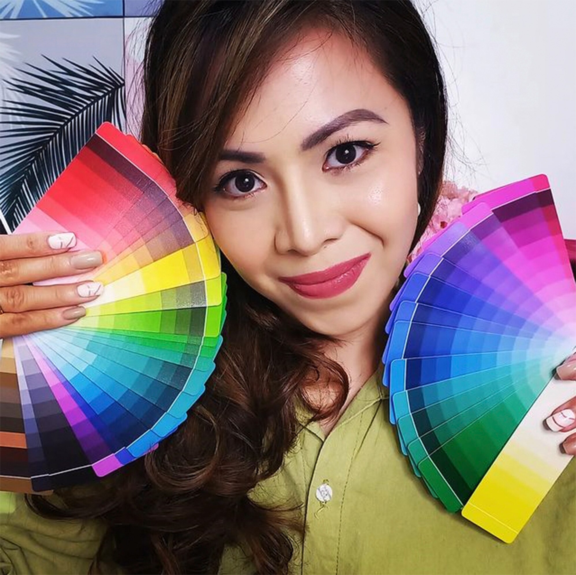 A woman holding color swatches to her face.