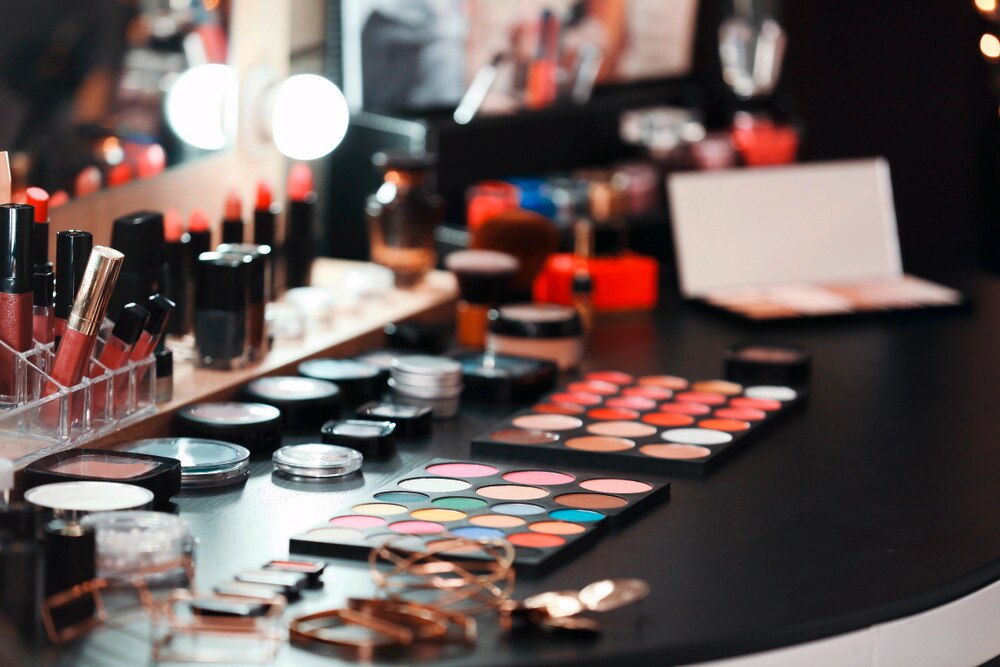 Makeup products and tools on a black vanity tabletop.
