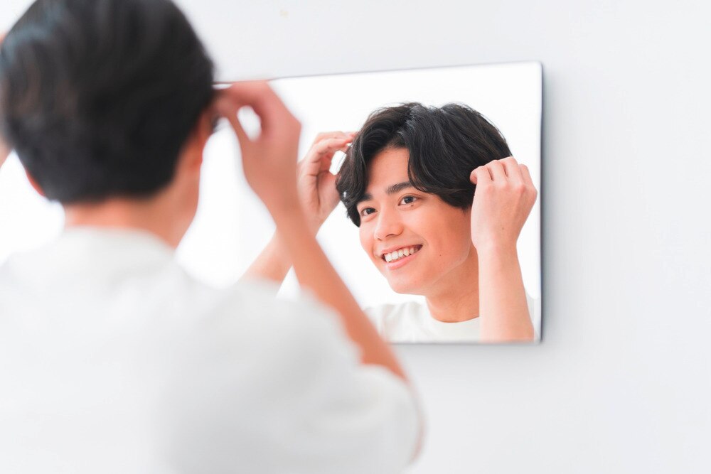 Smiling man styling his hair in front of the mirror.